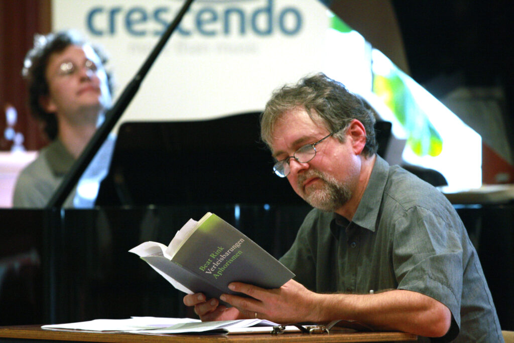 Beat Rink in ein Buch blickend vor Martin Helmchen am Piano.